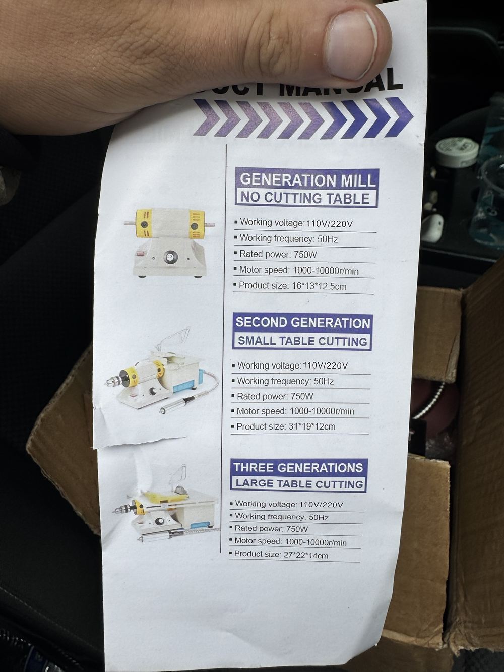 A printed product sheet held in one hand, showing three variants of a small bench mill: one with a polishing wheel and no table, one with a small cutting table and a flexible shaft, and one with a larger cutting table. Each is listed at 110 or 220 volts, 50 Hz, 750 W, 1,000 to 10,000 rpm